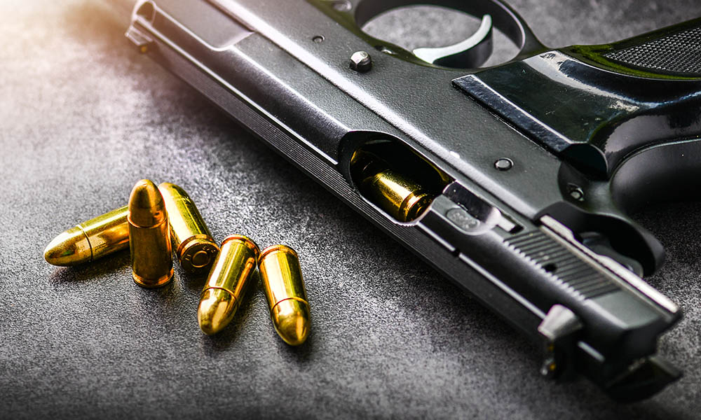Blog - What Happens When Your Home Insurance Doesn’t Cover Self-Defense Shootings - Gun Laying On A Table With Bullets Next to It