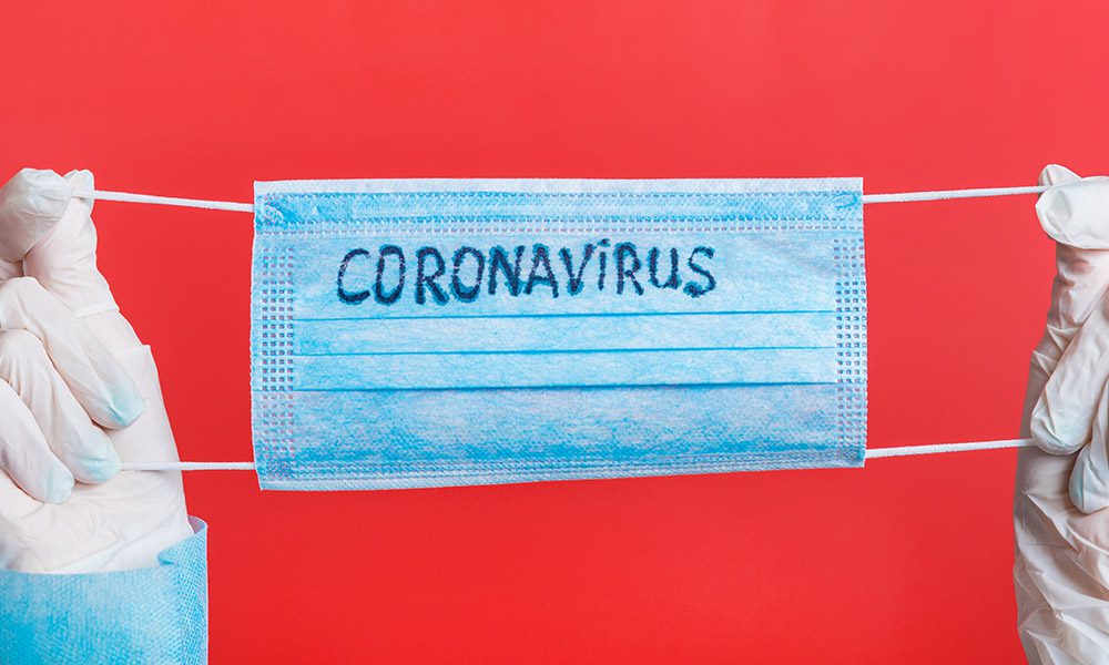 Blog - COVID-19 Announcement - Nurse Holding Up A Mask That Says Coronavirus On It