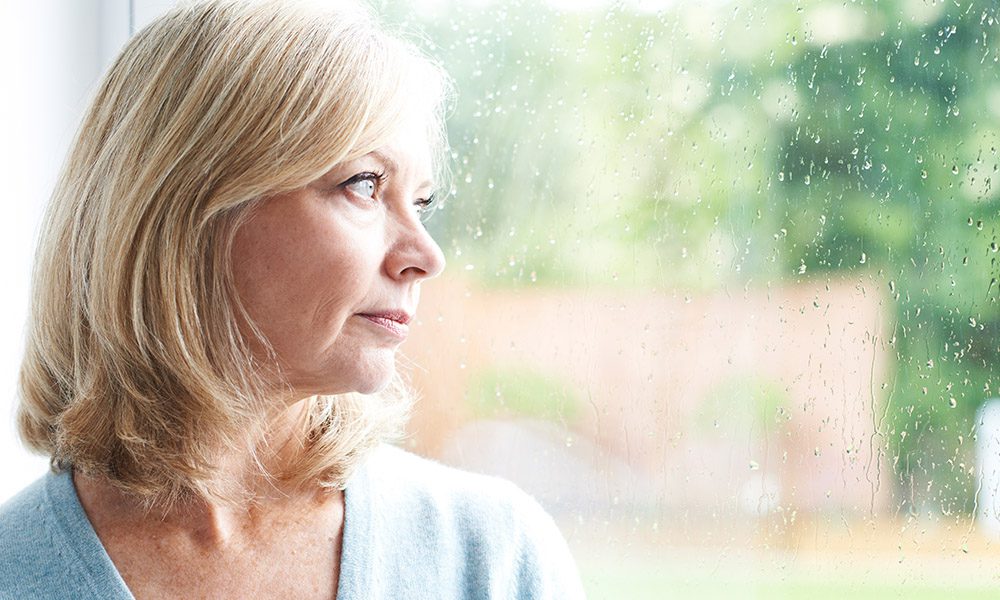 Blog - 4 Tips for Applying for Life Insurance After a Breast Cancer Diagnosis - Woman Looking Out A Window With Rain On It