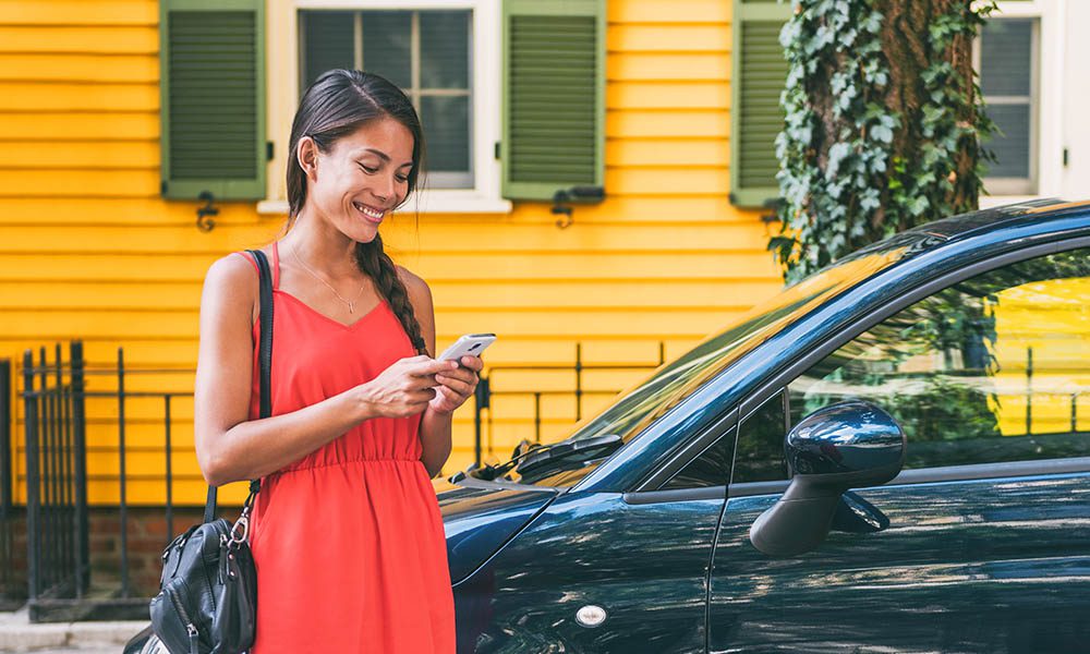 Blog - Woman Smiling at Phone While Walking to Her Car